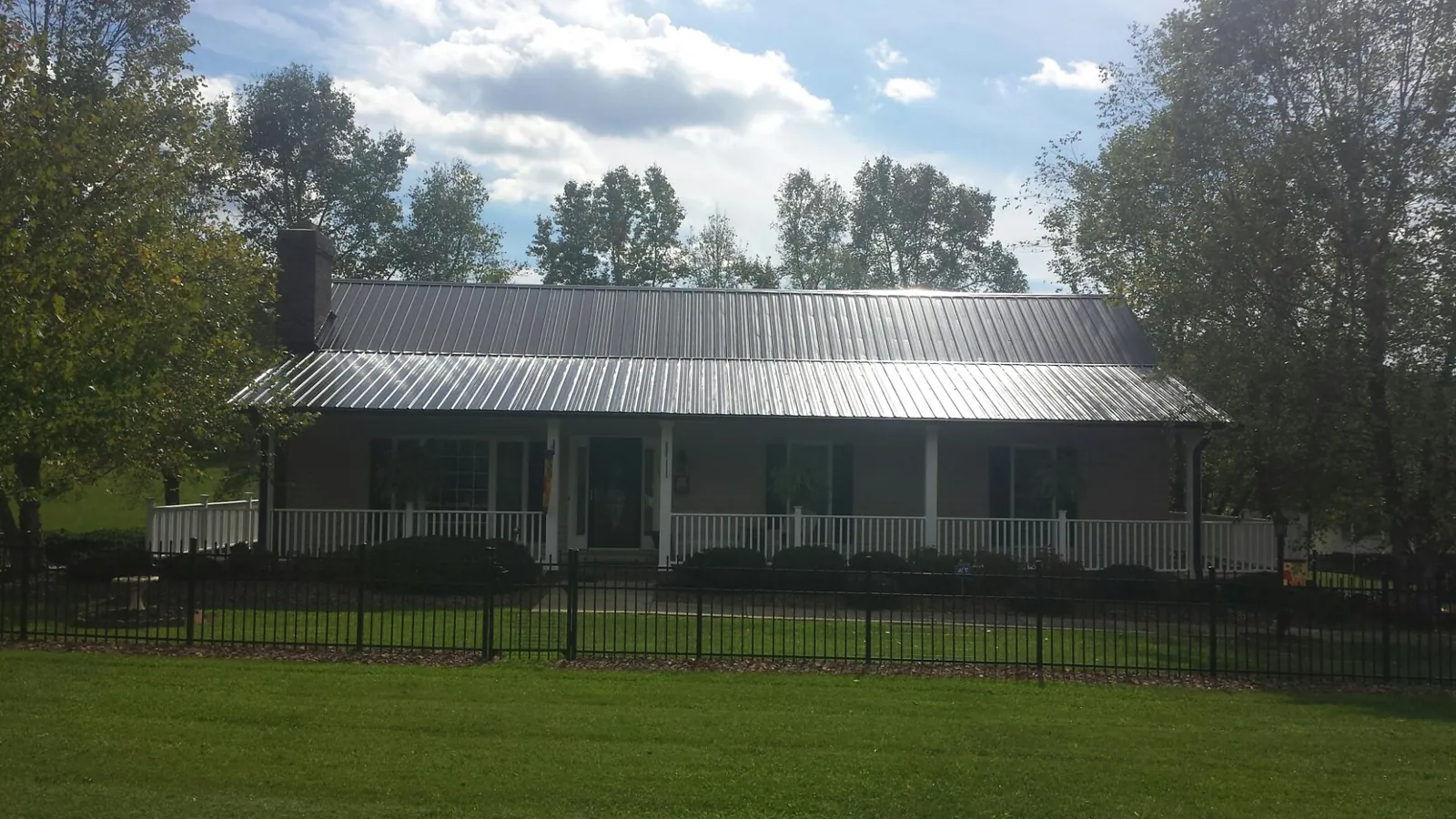 Gray metal roof on a brick ranch with a full width front porch — Gutter Guard Installation work by our crew in Kenner