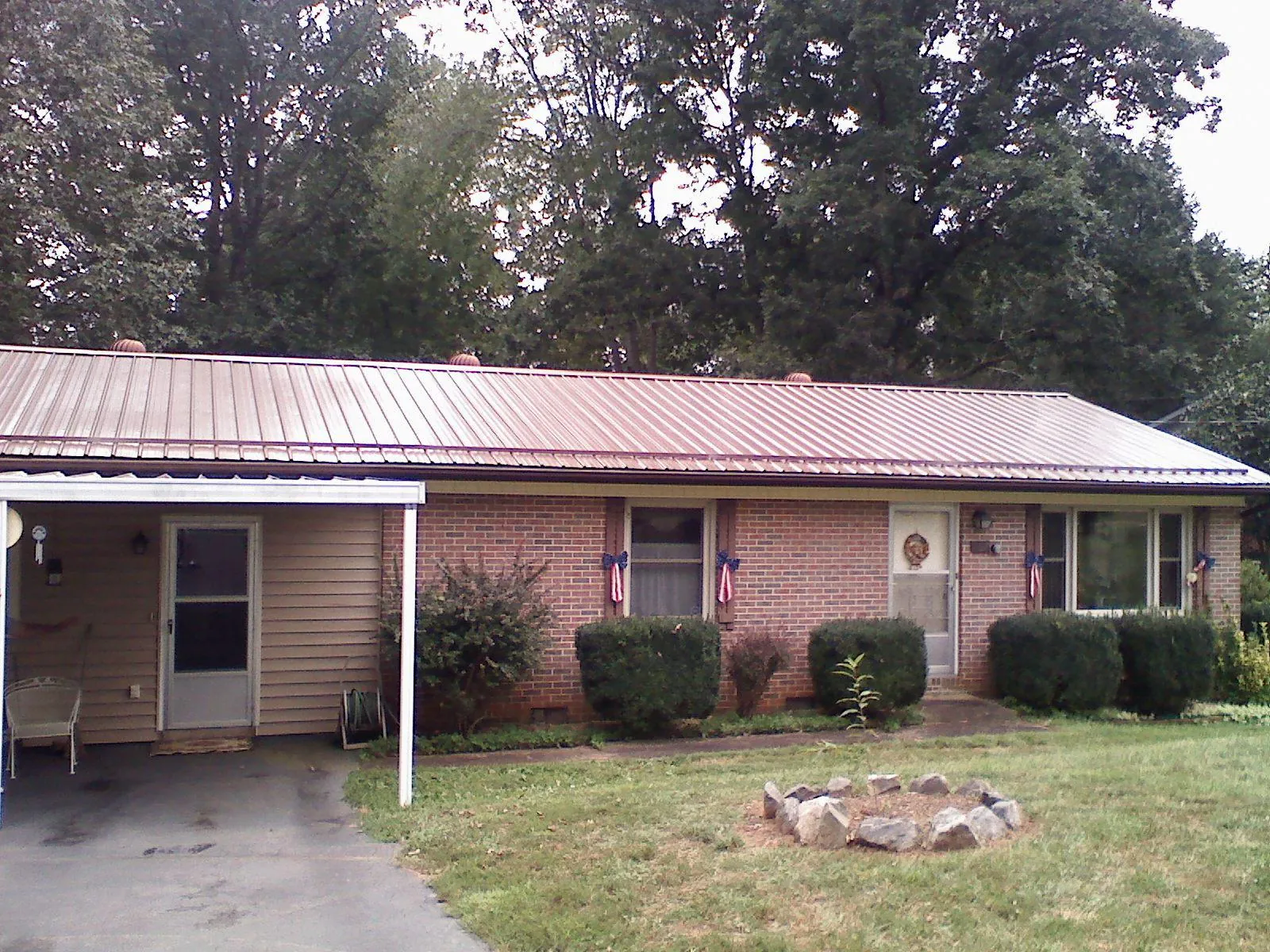 Bronze metal roof and carport on a brick ranch home — Roof Repair work by our crew in Kenner